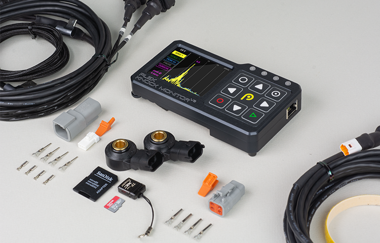 Knock Monitor V3 and all included accessories laid out, including sensor, cables, flash drive, and connectors.